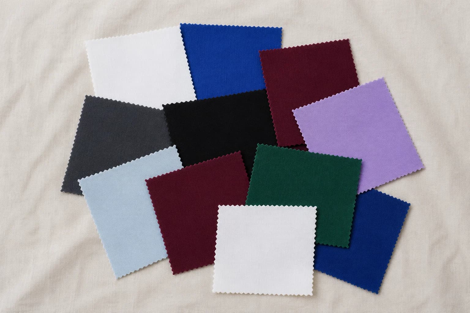 Cool Winter season fabric swatches arranged on linen — white, black, cobalt, burgundy, emerald
