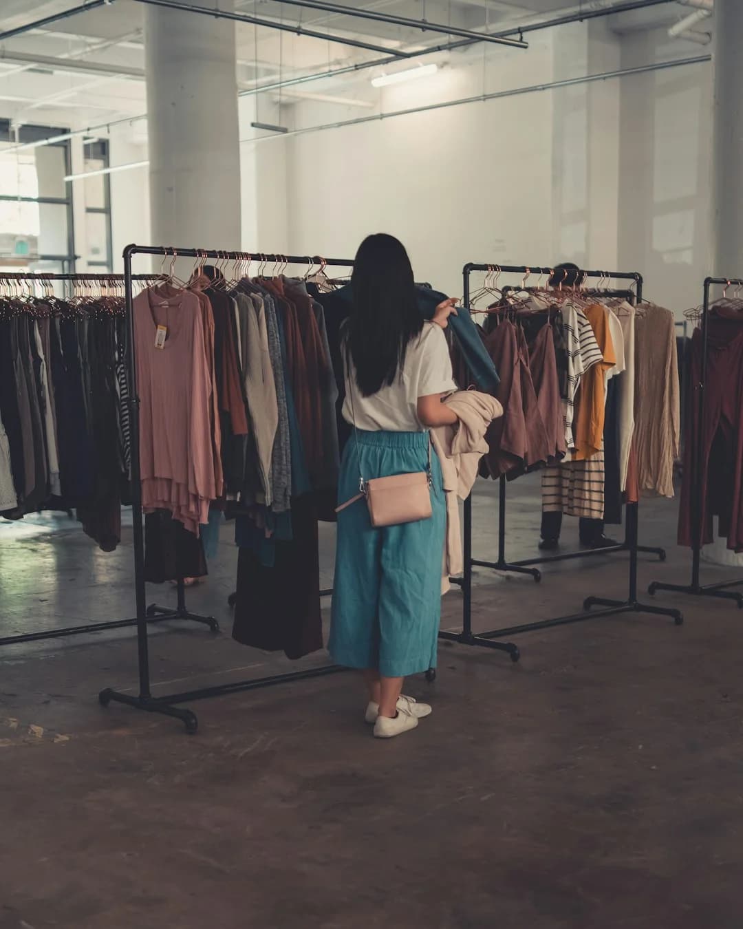 Shopper browsing a clothing rack, weighing the cost of getting color analysis right before buying